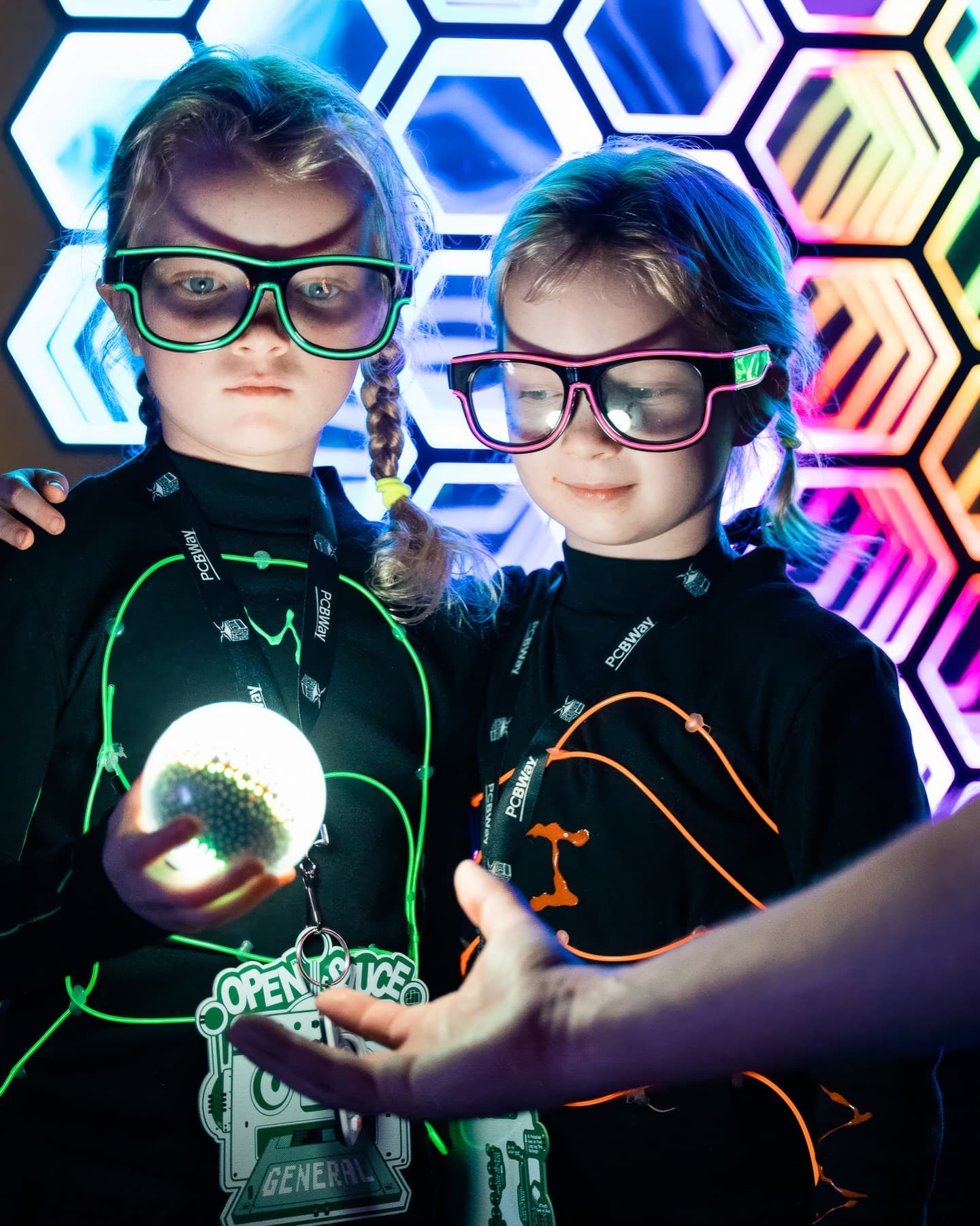 The two real sisters in their home-made glowing wire suits, holding the orb they built